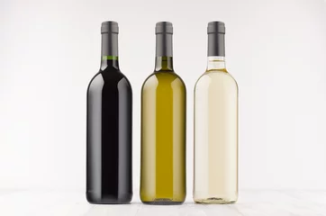 Rolgordijnen Three wine bottles  different colors - transparent, green, black- on white wooden board, mock up. Template for advertising, design, branding identity. © finepoints