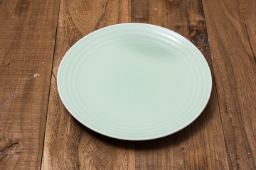 Green Plate on brown wooden background side view