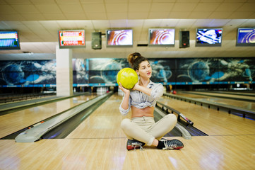 Girl with bowling ball on alley played at bowling club.