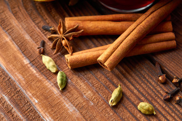 Autumn warming drink. Hot mulled wine, with lemon, anise, cinnamon, cloves, cardamom. Autumn dark still life. Mulled wine with slice of lemon and spices.