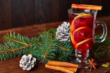 Christmas mulled wine with spices in cup on dark background. Hot mulled wine, with lemon, anise,...