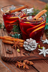 Christmas mulled wine with spices in cup on dark background. Hot mulled wine, with lemon, anise, cinnamon, cloves, cardamom. Autumn dark still life. Mulled wine with slice of lemon and spices.