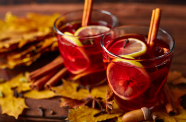 Autumn warming drink. Hot mulled wine, with lemon, anise, cinnamon, cloves, cardamom. Autumn dark still life. Mulled wine with slice of lemon and spices.