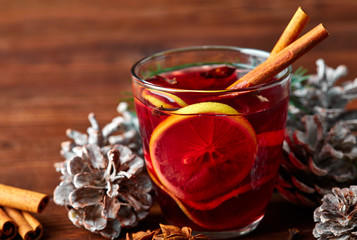 Christmas mulled wine with spices in cup on dark background. Hot mulled wine, with lemon, anise, cinnamon, cloves, cardamom. Autumn dark still life. Mulled wine with slice of lemon and spices.