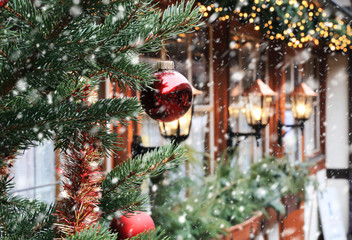 Christmas street decorations and falling snow - red ball, fir and bokeh lights