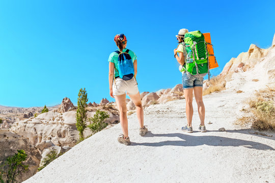Two happy active women hiking together in a rock sandstone canyon in the desert, travel and outdoor vacation concept