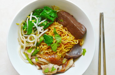 dry Chinese egg noodles topping duck meat and bean sprout on bowl and stainless chopsticks
