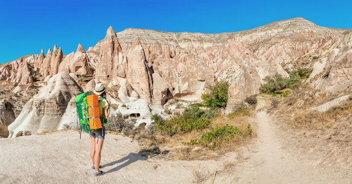 Young happy active tourist woman with backpack travel and trekking at Cappadocian deserted canyons and valleys, Turkey.
