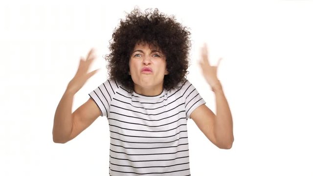 indoor portrait of angry displeased woman in casual t-shirt gesturing in furious manner shouting loudly having aggression over white background. Concept of emotions