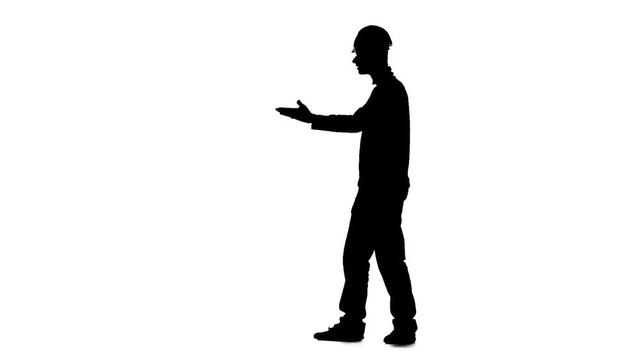 Builder in a helmet hammers a nail with a hammer. Silhouette. White background. Slow motion