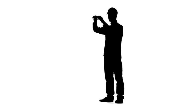 Builder measures roulette measurements for the drawing. Silhouette. White background. Slow motion