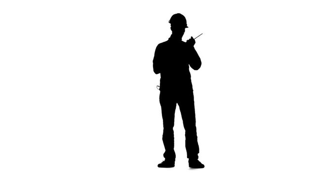 Engineer in a helmet works as a drill. Silhouette. White background. Slow motion