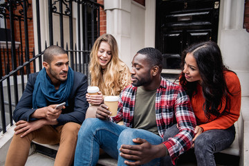 Multiracial group of friends having fun together in London. Two girls and two boys, talking and...