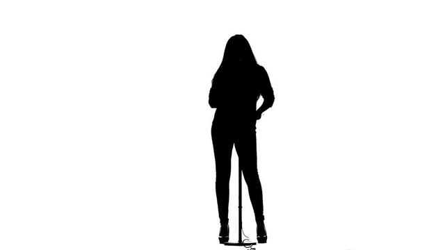 Girl sings melodic songs into the microphone. White background. Silhouette