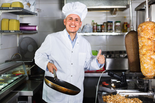 Man cook making kebab dish and looking satisfied holding thumbs up