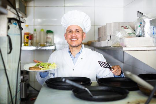 Smiling professional cook sitting on kitchen