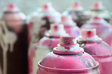A lot of dirty and used aerosol cans of bright pink paint. Macro photograph with shallow depth of...