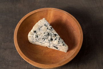 white cheese with mold vintage wooden plate stands on dark wooden table