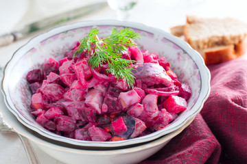 German traditional salad with beets, apple, egg and herring in a bowl, selective focus