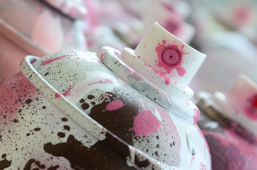 A lot of dirty and used aerosol cans of bright pink paint. Macro photograph with shallow depth of...