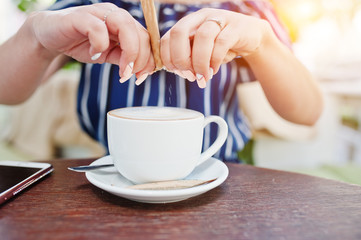 Close up hands with sugar and cup of coffee.