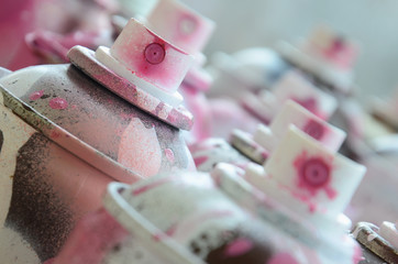 A lot of dirty and used aerosol cans of bright pink paint. Macro photograph with shallow depth of...