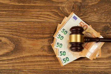 Judge gavel and money stack on wooden table.
