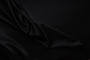 Fototapeta premium Dark black silky, satin fabric, wave, draperies. Beautiful textile backdrop. Close-up. Top view 