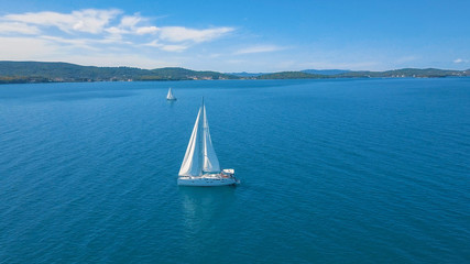 Fototapeta premium Aerial view of yacht sailing near beautiful Islands. Beautiful clouds in the background. Luxury yacht in the sea.