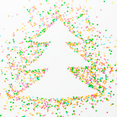 Christmas tree made of colorful bright confetti on white background. Flat lay, top view copy space
