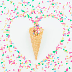 Heart symbol made of colorful bright confetti and waffle cone on white background. Flat lay, top view copy space. Love concept