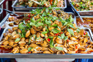 Fresh mollusc in the shop offer. A pile of fresh shells on a plate of a street store, Thailand.