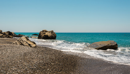 Fototapeta na wymiar Pissouri Bay pebble beach with large rocks in a sea, Cyprus