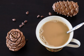 Coffee or milk tea chai with pine nuts cedar vegan milk. Black wooden background and cones of...