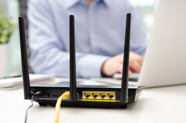 Wireless router and man using a laptop in office