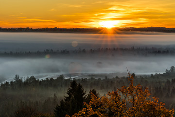 Sonnenaufgang über dem herbstlich vernebelten  Isartal bei Wolfratshausen in Bayern
