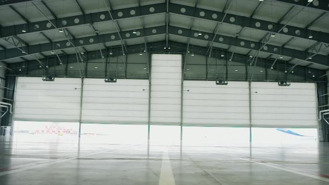 Big modern aircraft hangar with big gate at sunny summer day. Gate of the aircraft hangar
