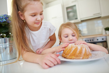Zwei Kinder naschen von Kuchen in der Küche