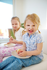 Zwei Kinder mit schlechter Laune essen Kuchen