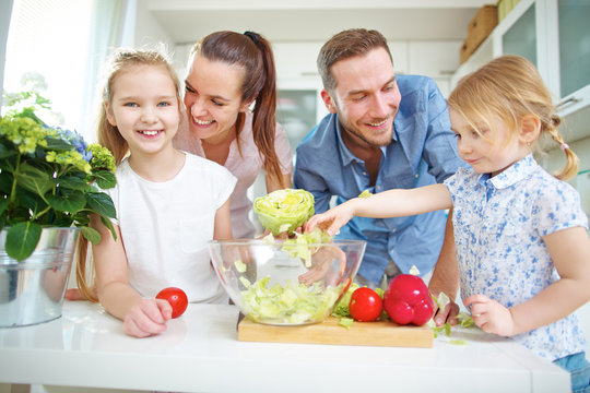 Familie und Kinder machen Salat in Küche