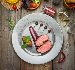Medallions of veal, with sauce on a plate. Wooden background