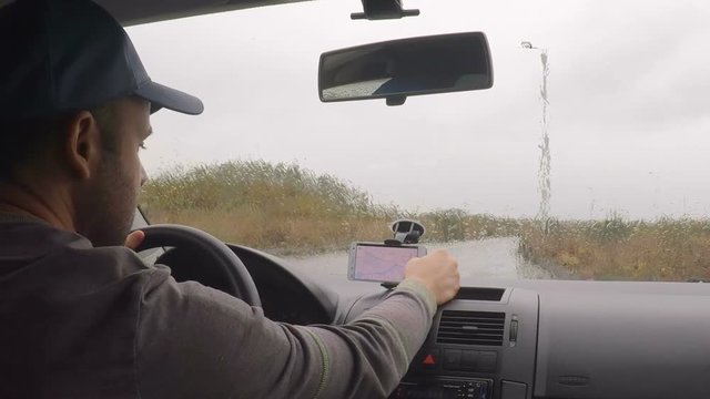 Smartphone with map gps navigation for direction, location. Man driver in modern car looking for directions in the map. Man is driving car in rainy, cloudy day. Rain. Business