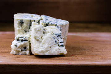 Danish blue or roquefort cheese macro shot on the cutting board with coarse edges and moldy veins exposed.