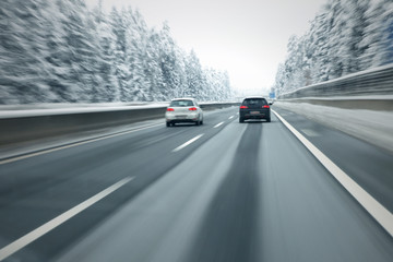 Motion blurred cars overtaking on slippery and frozen highway. Personal perspective used. - obrazy, fototapety, plakaty