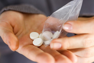 Treatment tablets. Close-up of a white pack pills in woman's fingers. Pours tablets from a package in hand