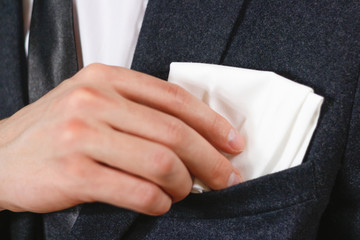 Obraz premium Close up hand puts a white handkerchief in the pocket of his black jacket