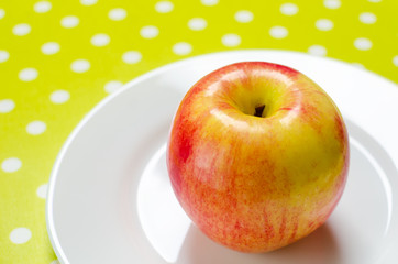 ripe red-yellow apple on a white plate