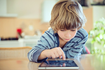 Little boy playing with digital pad at the table.