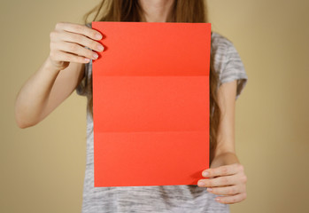 Girl showing blank red flyer brochure booklet. Leaflet presentation. Pamphlet hold hands. Woman...