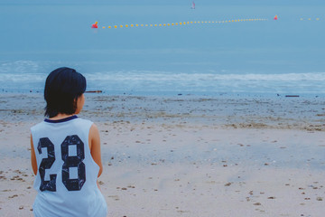 Young girl sitting on the beach in the early morning, added color filter
